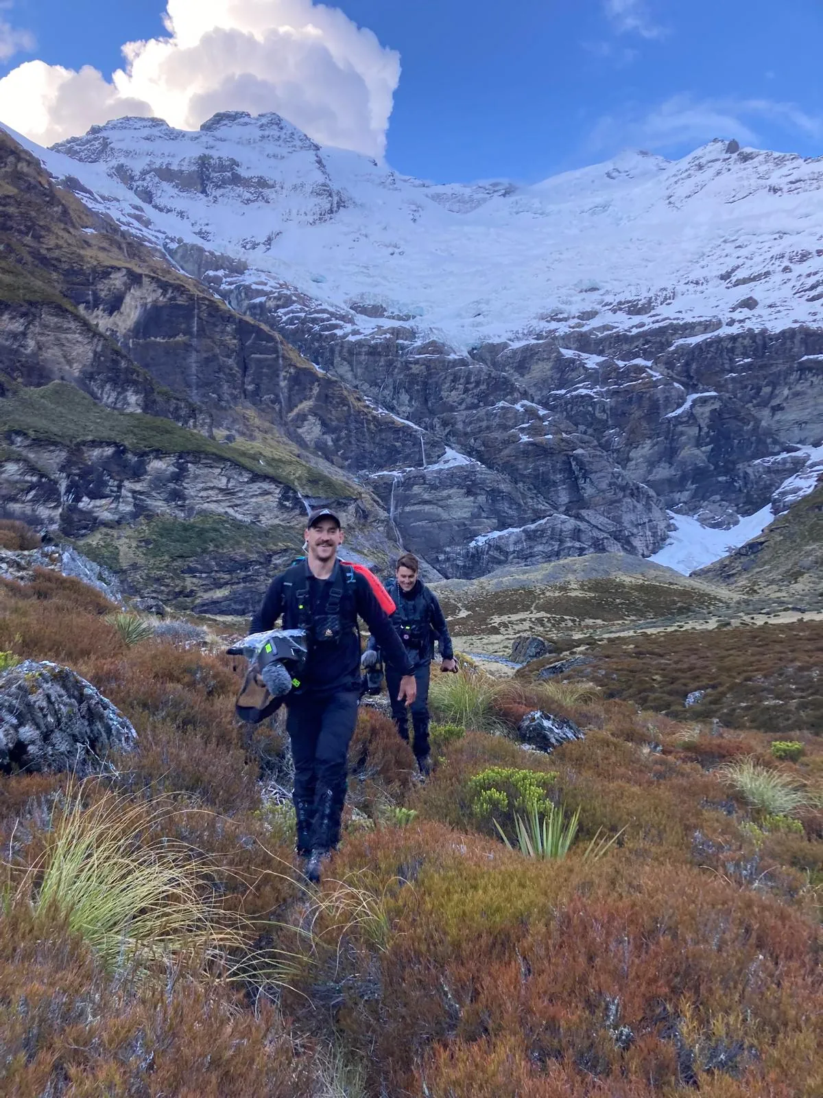 Dom hiking through mountain country during a television production